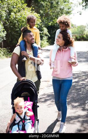 Glückliche Familie zu Fuß auf sonniger Straße Stockfoto