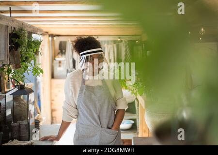 Frau in schützenden Gesichtsschutz arbeiten in der Pflanzenküserei Stockfoto