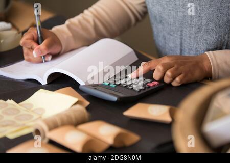 Nahaufnahme des Ladenbesitzers mit Taschenrechner, der das Buch ausfüllt Stockfoto