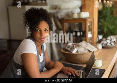 Portrait selbstbewusst weibliche Shop-Besitzer mit Laptop in der Pflanzenküterei Stockfoto