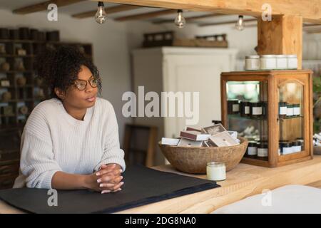 Nachdenkliche weibliche Ladenbesitzerin hinter dem Tresen Stockfoto