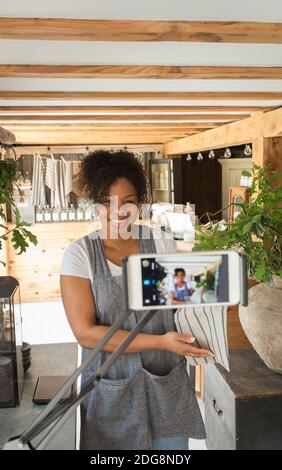Weibliche Ladenbesitzerin beim Filmen von Vlog mit Kamera-Telefon im Werk Kindergarten Stockfoto