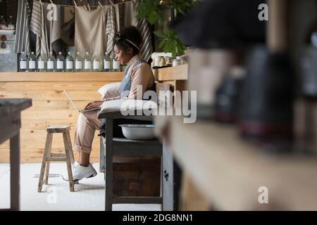Weibliche Ladenbesitzerin mit Laptop auf der Bank Stockfoto