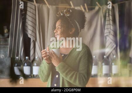 Nachdenkliche weibliche Ladenbesitzerin trinkt Kaffee Stockfoto