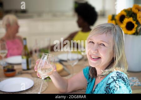 Portrait glückliche ältere Frau trinken Weißwein mit Freunden an Tabelle Stockfoto