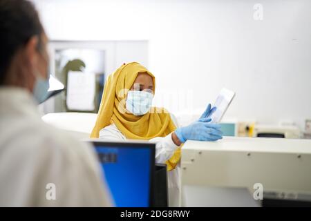 Wissenschaftlerin in Hijab und Gesichtsmaske mit digitalen Tablet Stockfoto