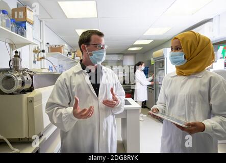 Wissenschaftler in Gesichtsmasken reden im Labor Stockfoto