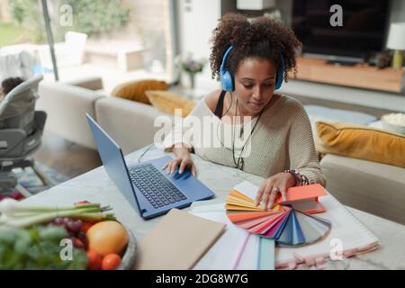 Weibliche Designerin mit Farbfeldern, die von zu Hause aus am Laptop arbeiten Stockfoto