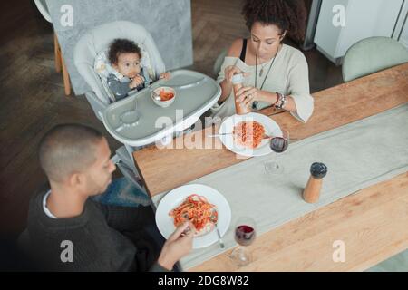 Familie essen Spaghetti am Esstisch und Hochstuhl Stockfoto
