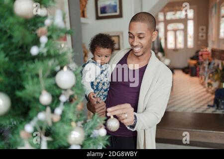 Glücklicher Vater und Baby Tochter Dekoration Weihnachtsbaum Stockfoto