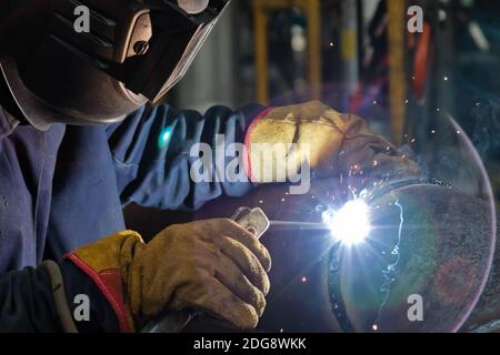 Schweißen arbeitet am Metallwärmetauscher mit manuellem Lichtbogenschweißen Stockfoto