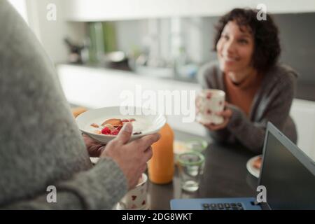 Pärchen beim Frühstück und beim Gespräch in der morgendlichen Küche mit Laptop Stockfoto