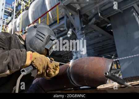 Schweißen arbeitet am Metallwärmetauscher mit manuellem Lichtbogenschweißen Stockfoto