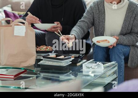 Pärchen genießen Essen zum Mitnehmen mit Essstäbchen im Wohnzimmer Stockfoto