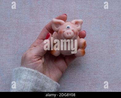 Halten Sie ein kleines rosafarbenes Marzipanschwein, um es zu essen Stockfoto