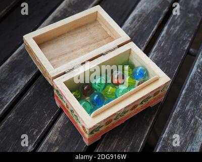 Bunte Glaskugeln in einer kleinen Holzkiste auf einem Alter Holztisch Stockfoto