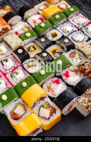 Sushi-Set. Verschiedene Arten von Maki und Nigiri Sushi. Heller und farbenfroher Service im Restaurant. Serviert auf Sushi-Brettern aus dunklem Stein. Riesige Sushi s Stockfoto