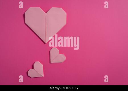 Origami Herzen mit farbigem Papier für Glückwünsche zum Valentinstag für verliebte Paare, auf rosa Hintergrund. Liebeskonzept Stockfoto