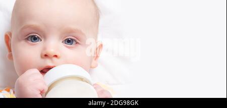 Bannerformat. Kaukasischen Säugling mit Baby-Milchflasche. Nahaufnahme. Speicherplatz kopieren. Konzentrieren Sie sich auf Babys Augen. Künstliche Fütterung. Milchpulver für Babys. Stockfoto