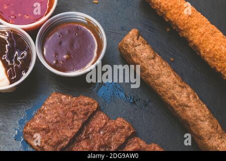 Verschiedene gebratenes Fleisch. Verschiedene Arten von Schweinefleisch Steak, Hühnerfilet und Rinderwurst mit einigen Saucen auf dunklem Holzhintergrund. Gegrillt und Barb Stockfoto