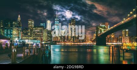 New York City Brooklyn Bridge und die Skyline von Manhattan bei Nacht beleuchtet mit Vollmond Overhead. Stockfoto