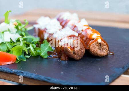 Amerikanische Junk-Food in einer einfachen Zusammensetzung. Knusprig gebratene Würstchen oder Hot Dog mit Mayo und Ketchup-Sauce und gehackte Zwiebel. Etwas Gemüse um lik Stockfoto