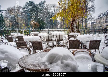 Stühle und Tische im Restaurant an der Passer Promenade in Meran, mit Schnee verkettet. Keine Anzeichen von Aktivität, weil COVID-19. Stockfoto