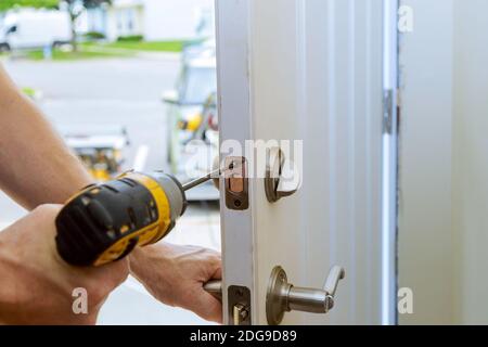 Mann, der den Türknopf repariert. Nahaufnahme der Hände des Arbeiters, der neuen Türschlosser installiert Stockfoto