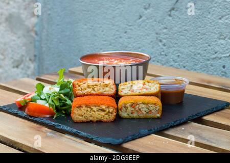 Klassische, italienische arancini. Frittierte Reisbällchen mit Hackfleisch und etwas Gemüse im Inneren. Leckere knusprige Speisen mit Erdnusssauce und Tomatensuppe Stockfoto