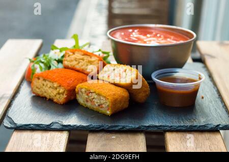 Klassische, italienische arancini. Frittierte Reisbällchen mit Hackfleisch und etwas Gemüse im Inneren. Leckere knusprige Speisen mit Erdnusssauce und Tomatensuppe Stockfoto