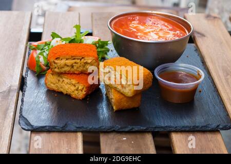 Klassische, italienische arancini. Frittierte Reisbällchen mit Hackfleisch und etwas Gemüse im Inneren. Leckere knusprige Speisen mit Erdnusssauce und Tomatensuppe Stockfoto