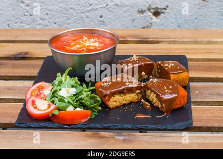 Klassische, italienische arancini. Frittierte Reisbällchen mit Hackfleisch und etwas Gemüse im Inneren. Leckere knusprige Speisen mit Erdnusssauce und Tomatensuppe Stockfoto