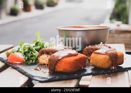 Klassische, italienische arancini. Frittierte Reisbällchen mit Hackfleisch und etwas Gemüse im Inneren. Leckere knusprige Speisen mit Erdnusssauce und Tomatensuppe Stockfoto