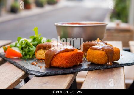 Klassische, italienische arancini. Frittierte Reisbällchen mit Hackfleisch und etwas Gemüse im Inneren. Leckere knusprige Speisen mit Erdnusssauce und Tomatensuppe Stockfoto