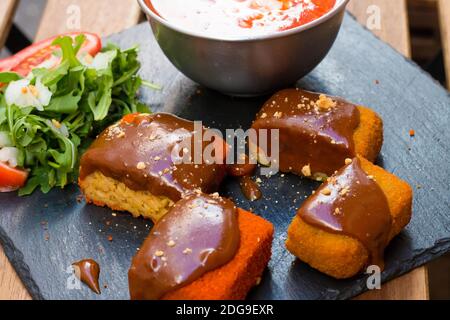 Klassische, italienische arancini. Frittierte Reisbällchen mit Hackfleisch und etwas Gemüse im Inneren. Leckere knusprige Speisen mit Erdnusssauce und Tomatensuppe Stockfoto