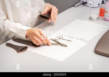 Die Hände des Manikuristen legen die Manikürenwerkzeuge auf den Tisch, auf den sie sich vorbereiten Maniküre Stockfoto