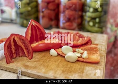 Geschälte Knoblauch und gehackte rote Paprika liegen auf einem Schneidebrdplatte Stockfoto