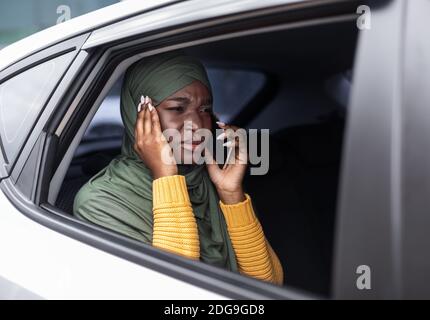 Schwarze Muslimische Dame Leidet Schlechte Verbindung Beim Sprechen Auf Handy Im Auto Stockfoto