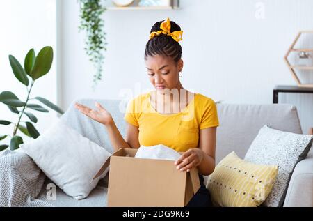 Frustriert schwarze Frau Auspacken falsche Box, Lieferfehler Stockfoto