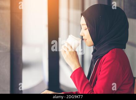 Moderne muslimische Frau, die mit einem Take-away über die Straße geht Kaffee Stockfoto