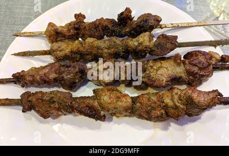 Vier frische Kebabs auf dem weißen Teller bereit zum Essen Stockfoto