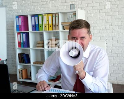 Der wütende Boss schreit in ein Megaphon. Stockfoto