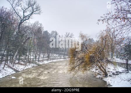 Das schmutzige Wasser des Passers nach einem starken Schneefall und seine Uferpromenade in Meran, Italien, bedeckt von nassem Schnee. Stockfoto