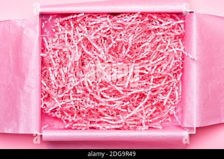 Box mit zerkleinerten rosa Papier Verpackungsmaterial. Lieferung von zerbrechlichem Gegenstand. Hintergrund- und Kopierbereich Stockfoto