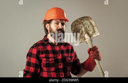 Bauarbeiter in Hut. Ingenieur Architekt in Schutzhelm. Brutaler Techniker Baumeister. Fabrikarbeiter Mechaniker. Industriearbeiter in Helm. Mann halten Schaufel in Handschuhen. Stockfoto