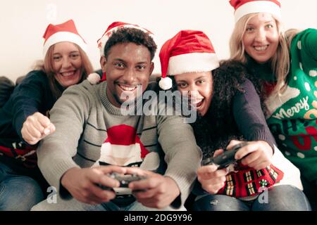 Millennial Menschen Spaß mit Videospielen Konsole auf weihnachten Zeit. Familie spielt den ganzen Tag Videospiele in der Wohnung. Weihnachten und Technolo Stockfoto