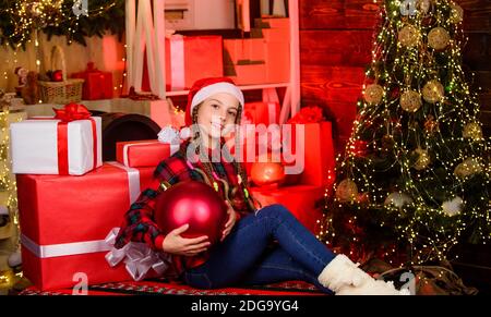 Einrichtungsgeschäft. Lieblingsfarbe. Roter Stil. Verbreiten Sie Liebe. Winterurlaub. Kleine niedliche Mädchen mit großen Ball weihnachtsbaum. Weihnachtsstimmung. Weihnachtskonzept. Kind fancy santa genießen Feier Neujahr. Stockfoto