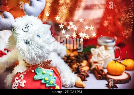 Weihnachtsdekor - weißes Spielzeug Rentier mit Sternen in den Händen, Mandarinen, Cookies und hellen Stern Form b Stockfoto