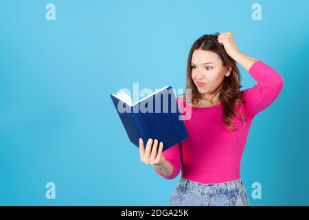 Nahaufnahme einer jungen Frau, die ein Tagebuch hält oder ihr Haar wegen eines Fehlers herausreißt, isoliert auf blauem Hintergrund Stockfoto