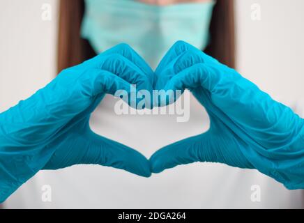 Eine Nahaufnahme einer Ärztin mit blauen medizinischen Handschuhen Zeigt das Herz-Symbol mit ihren Händen Stockfoto